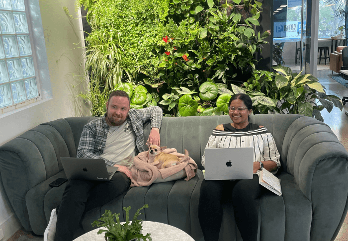 Two office workers on couch with a dog