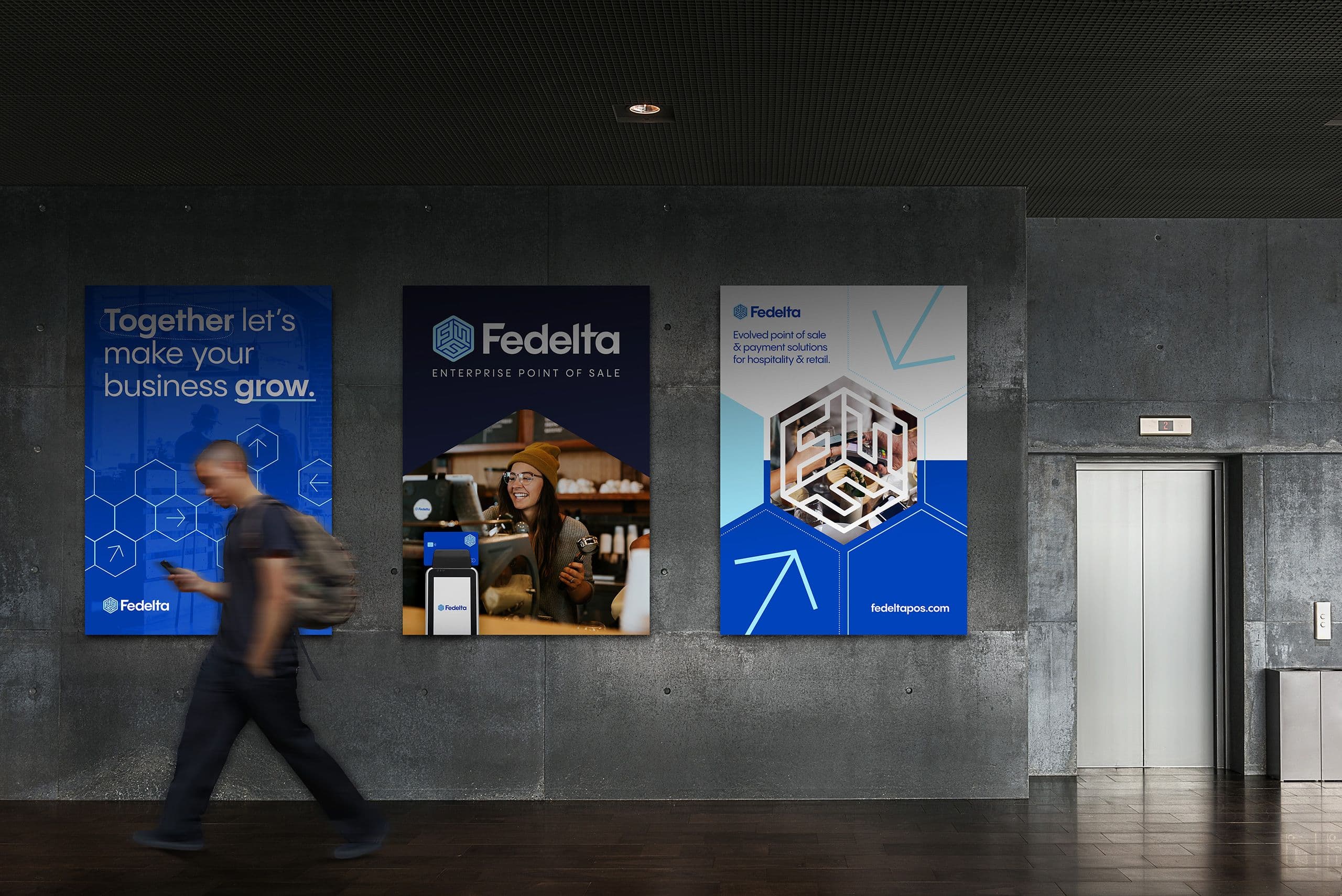 Man walking by three Fedelta posters in a lobby