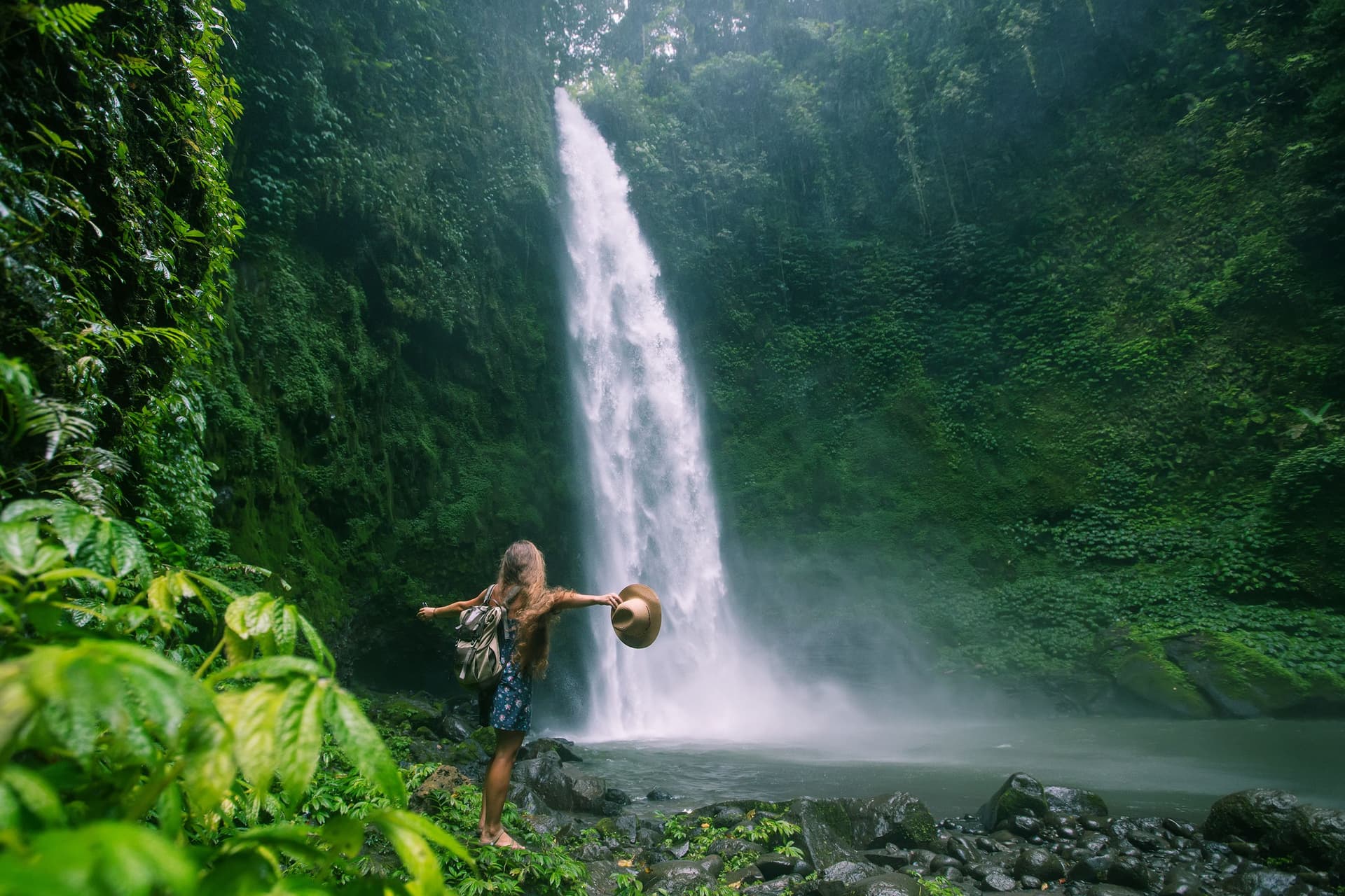 Woman embracing the view of a waterfall in a luscious green location