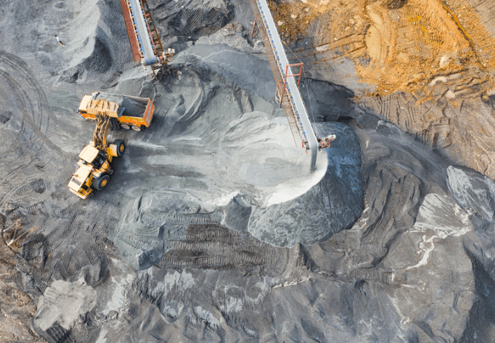 Aerial shot of mine site, featuring cranes and trucks