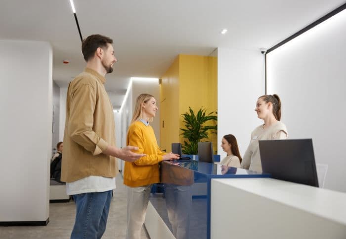 Man and woman smile at medical centre receptionist