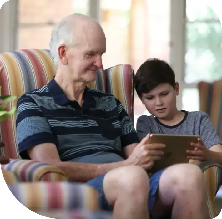 An older man and a boy looking at a tablet at home