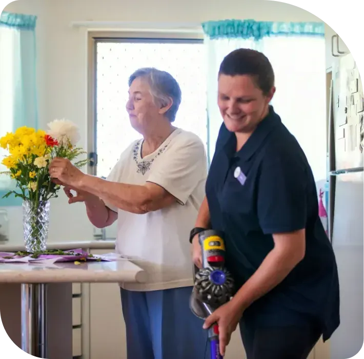 A care worker helping a woman arrange flowers