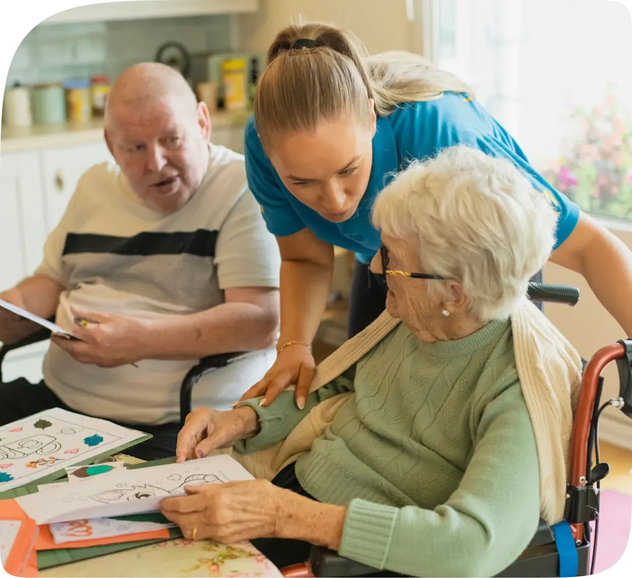 An aged care worker helping two residents with an art activity