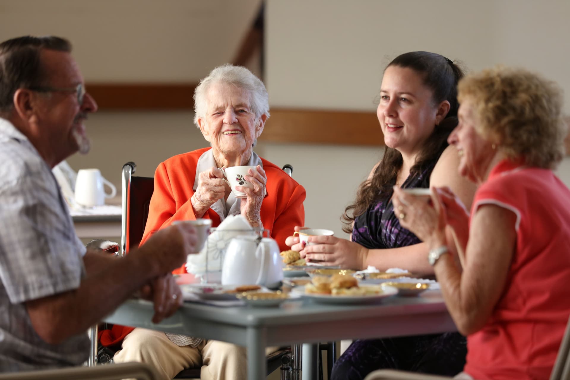 An elderly woman having morning tea with her family at a table