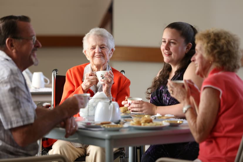 An elderly woman having morning tea with her family at a table