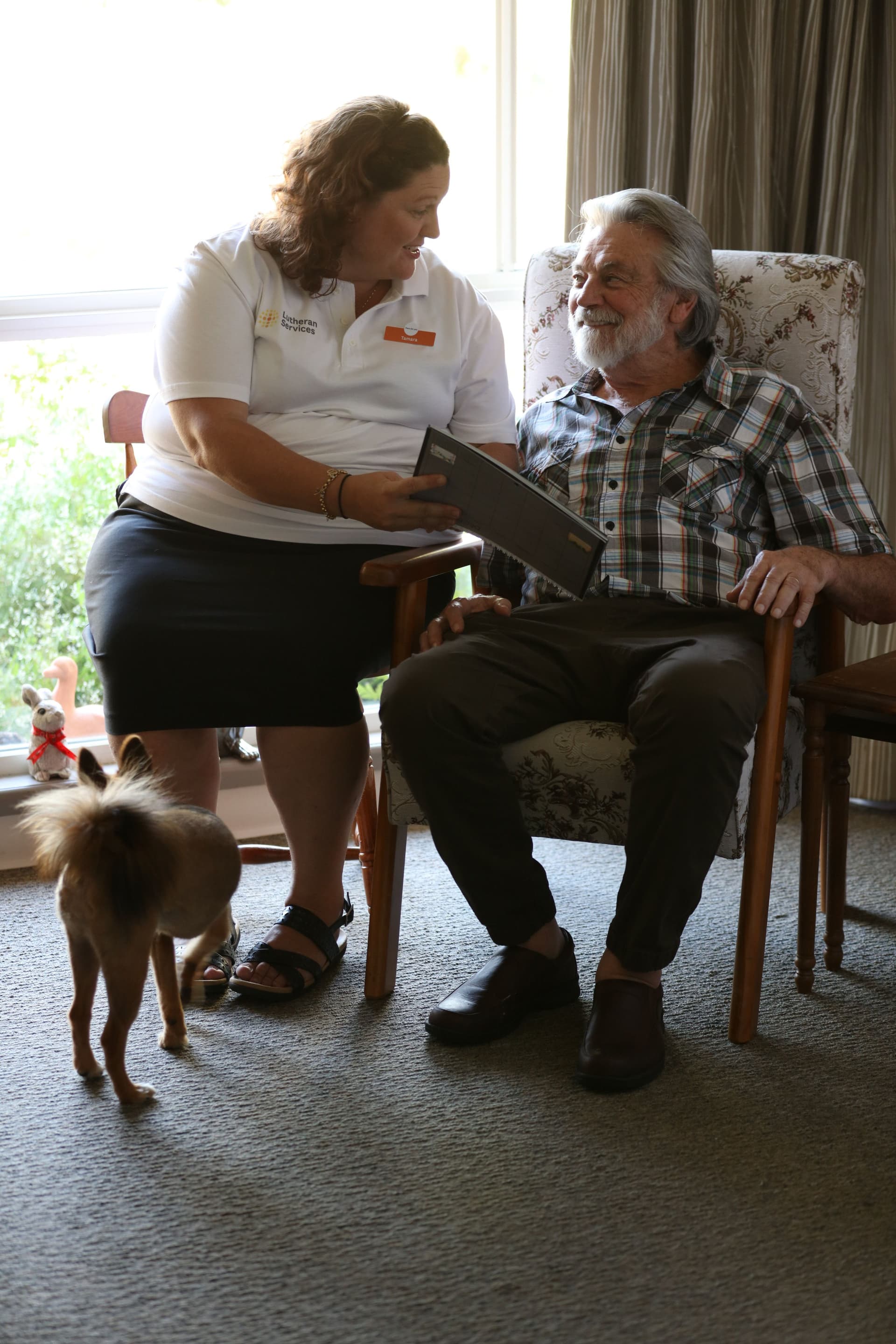 A woman sitting with an older man reading to him