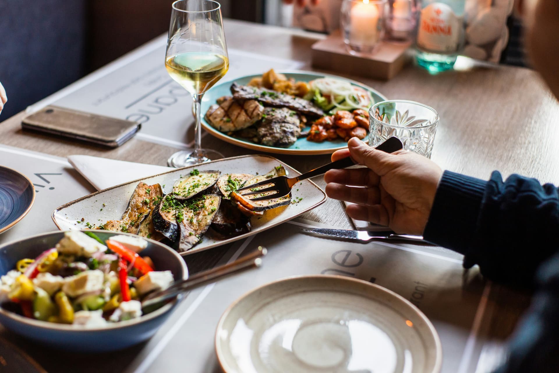 person holding fork eating food at a restaurant