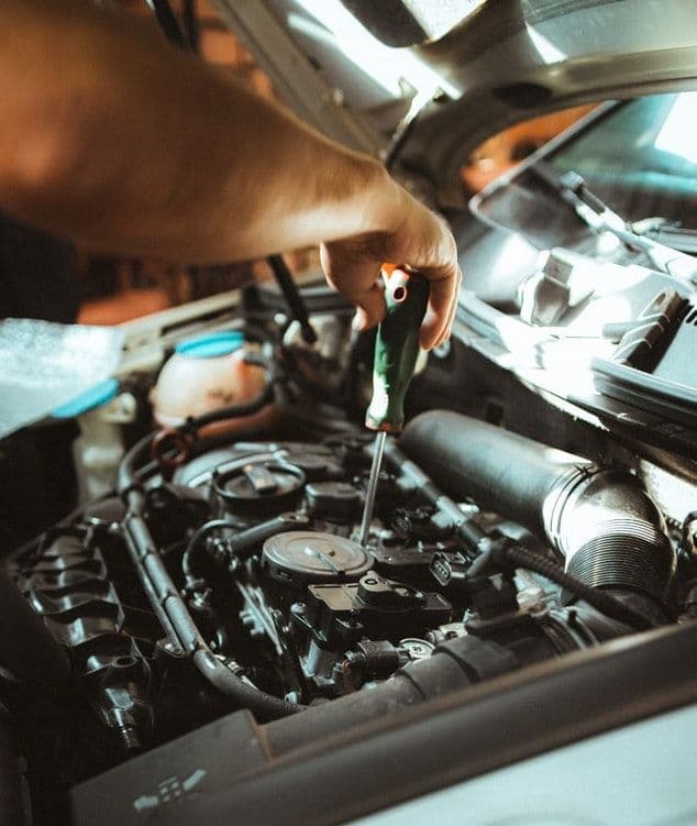 a mechanic looking under the hood of a car
